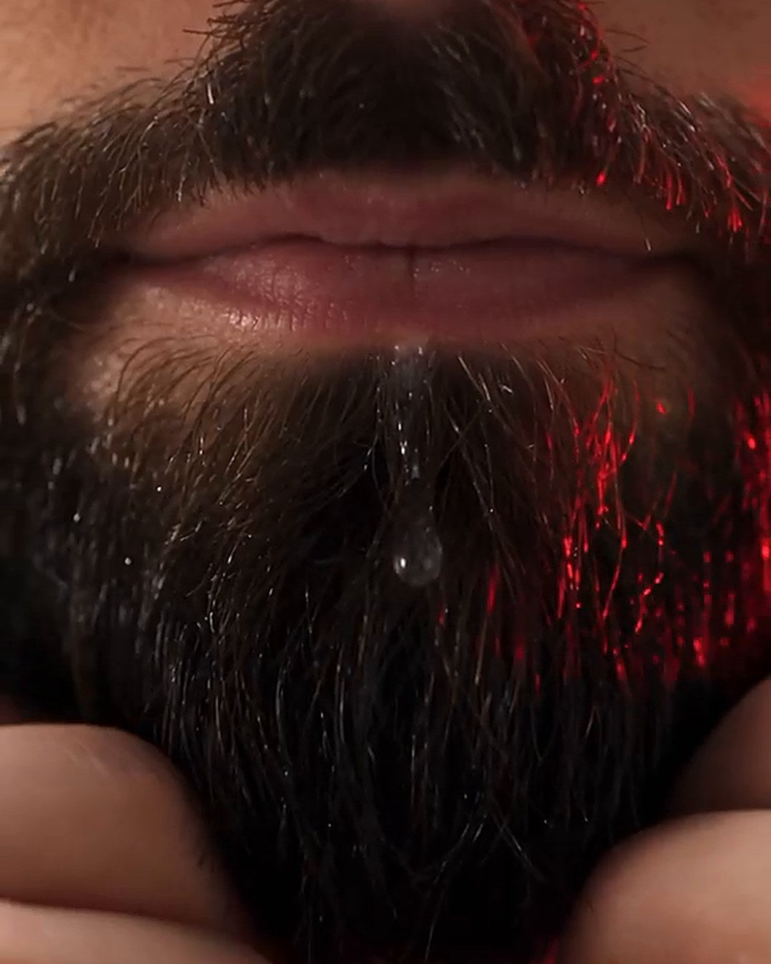 Close-up of a full, groomed beard with a drop of serum