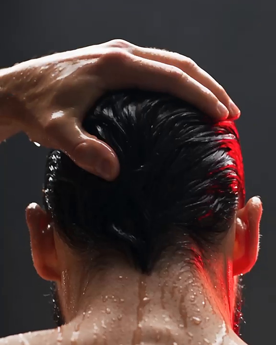 Man washing his hair in the shower under dramatic red light