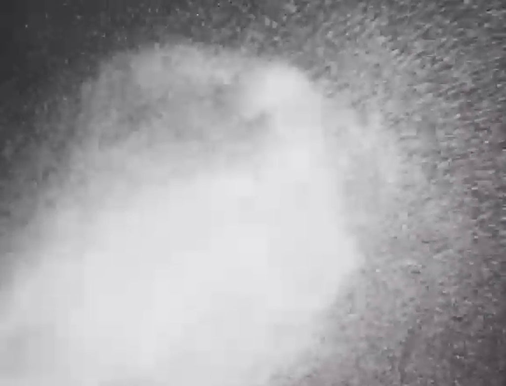 Fine fragrance mist spray cloud against a dark background